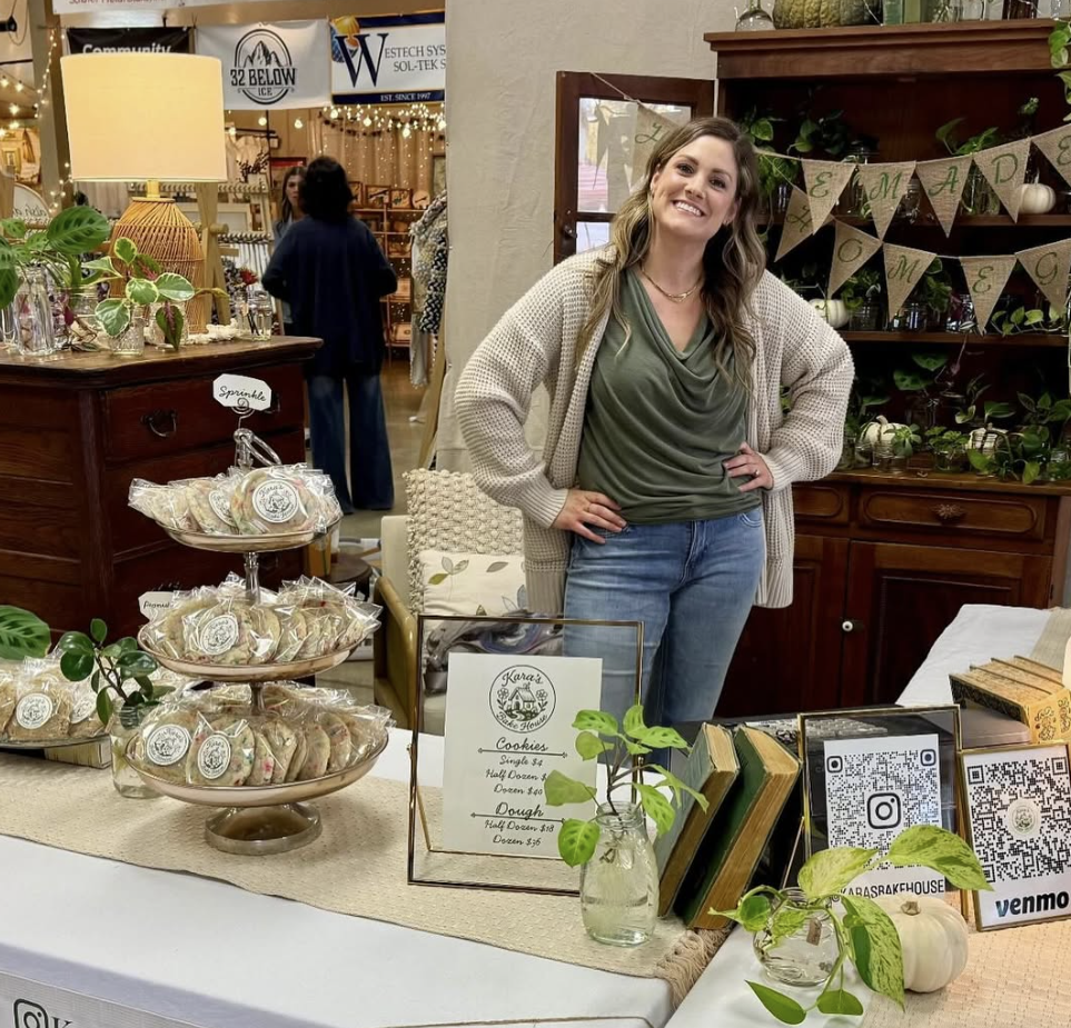 Kara smiling behind a market display of individually packaged cookies